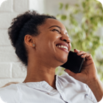 A woman smiles as she speaks with someone on a mobile phone.  